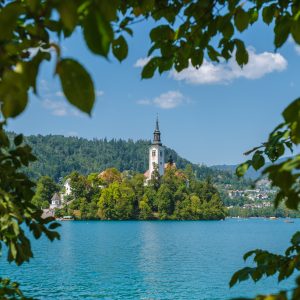 A serene view of Lake Bled, Slovenia, with its iconic island church framed by lush foliage