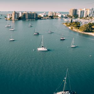 Beautiful aerial view of yachts sailing in a open blue sea near port city